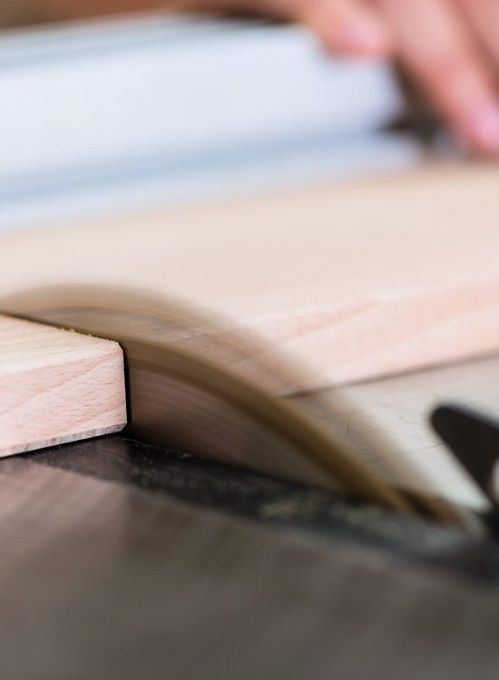 Carpenter cutting wooden board with circular saw